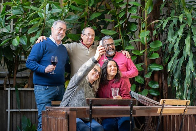 Pessoas maduras em uma mesa levantando taças ao posar para uma foto para ilustrar o conteúdo sobre turismo em grupo para pessoas acima de 50 anos